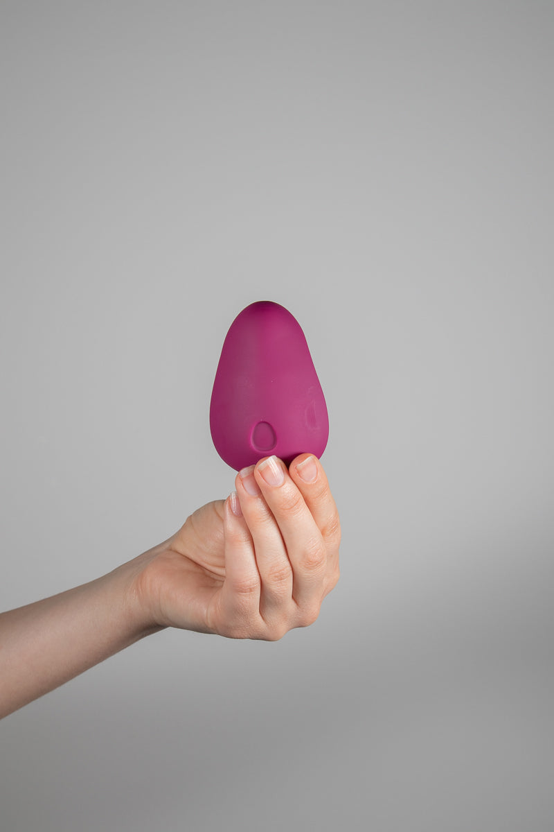 Dam Pom Plum vibrator held in hand showing top side 