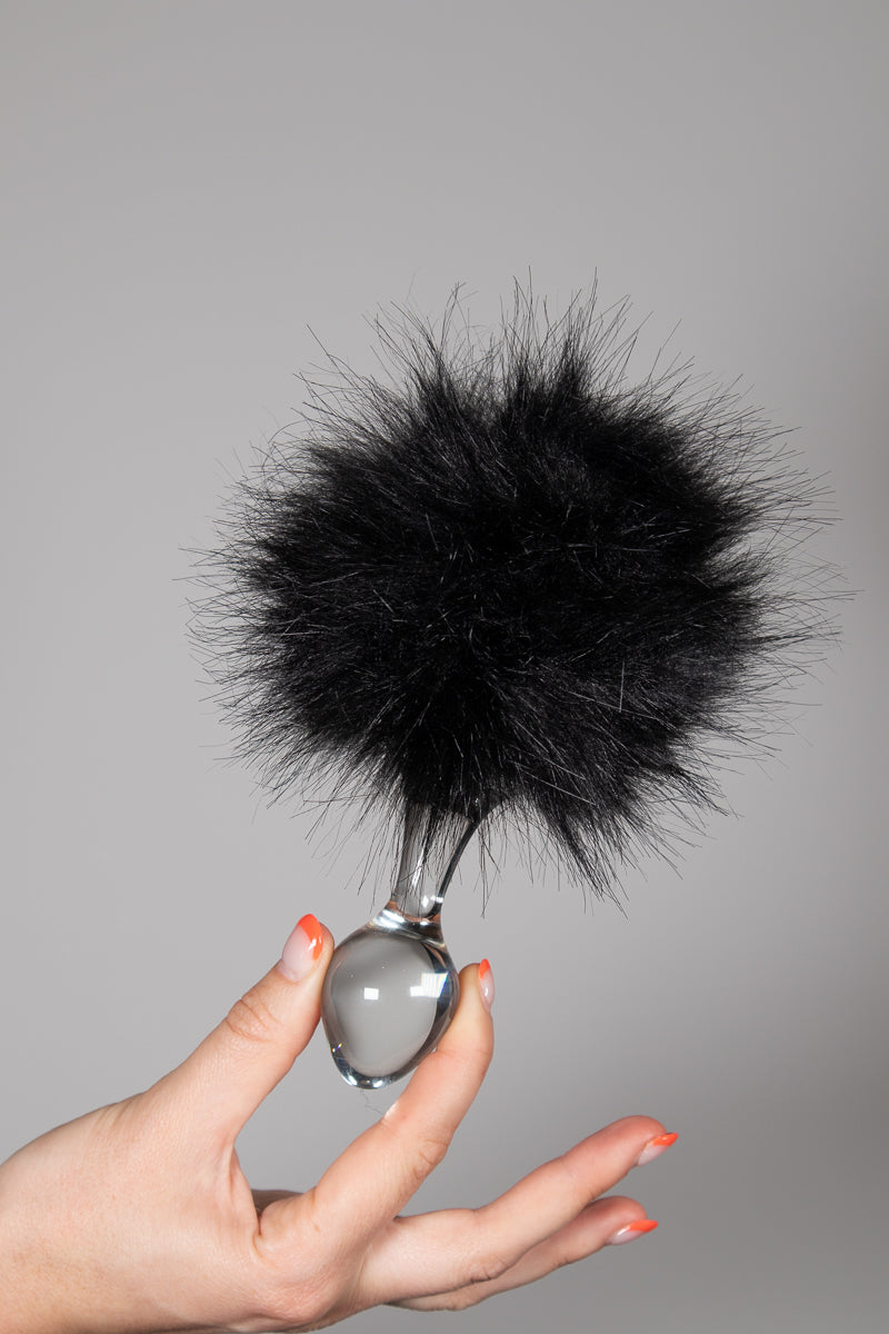 a hand holding crystal delights black faux fur bunny tail